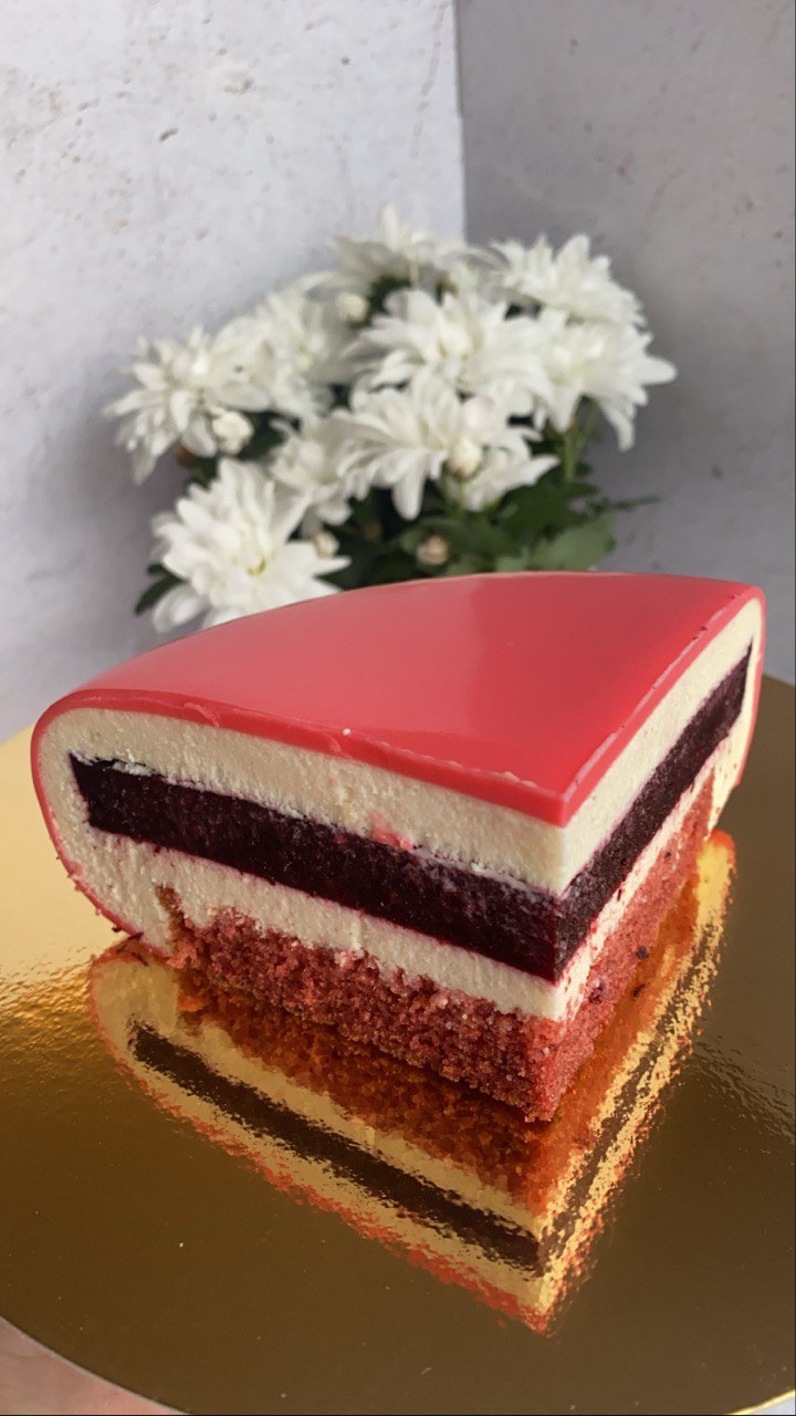 Red mirror-glaze mousse cake slice with berry layer