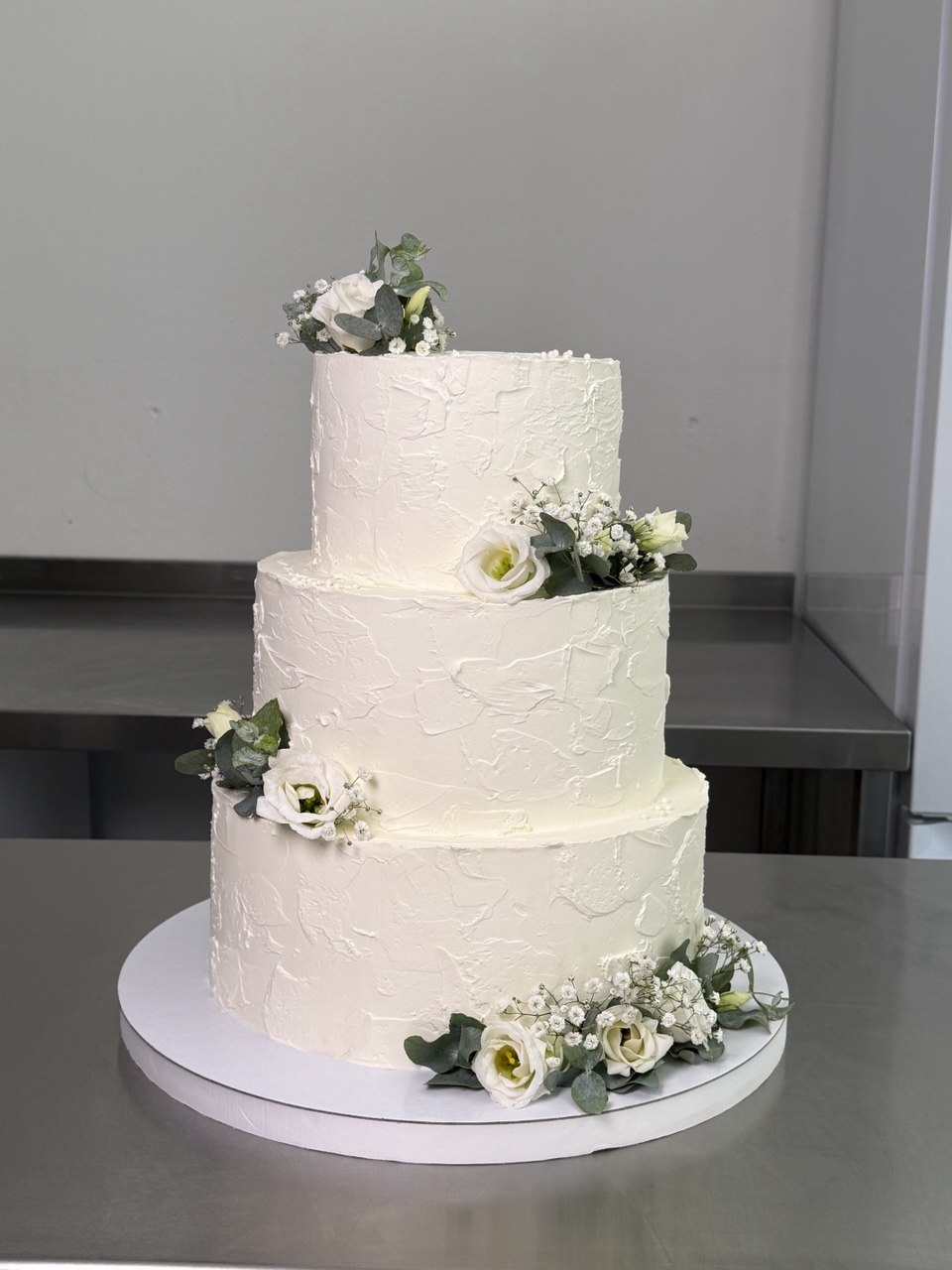 Three-tier textured wedding cake with white flowers